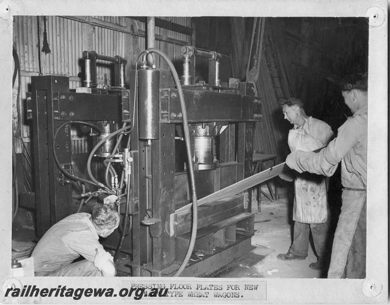 P00137
Workmen operating a press machine pressing floor plates for new AE class wheat wagons, MRWA Workshops, Midland, internal view.
