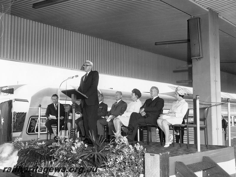 P00303
Ceremony for the launch of the Prospector railcar, East Perth Terminal, dignitary giving a speech, other official guests seated behind
