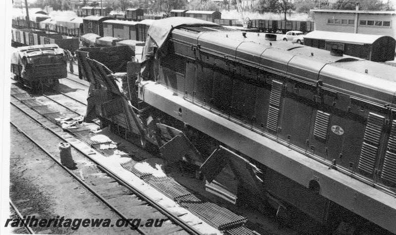 P01024
2 of 10 views of the derailment of A class 1501 at Northam Station, ER line. View shows loco on top of wagons looking forward, date of derailment 2/11/1961
