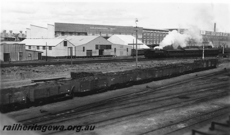 P01692
Fremantle railway yard, view looking towards south east with view of Goldsborough Mort and Elder Smith wool stores, train on suburban working, rake of open wagons loaded with coal and ash.
