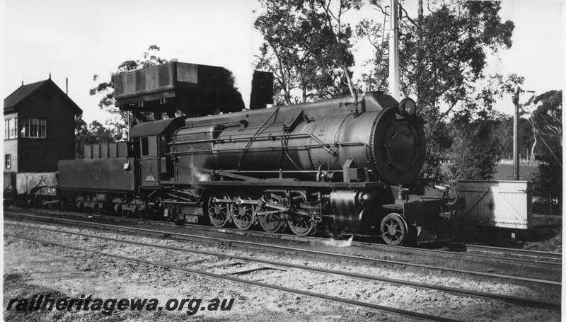 P01697
S class 476, Koojedda, ER line, hauling a goods train, side and front view, wooden signal box, water tower with a cast iron tank, signal post.

