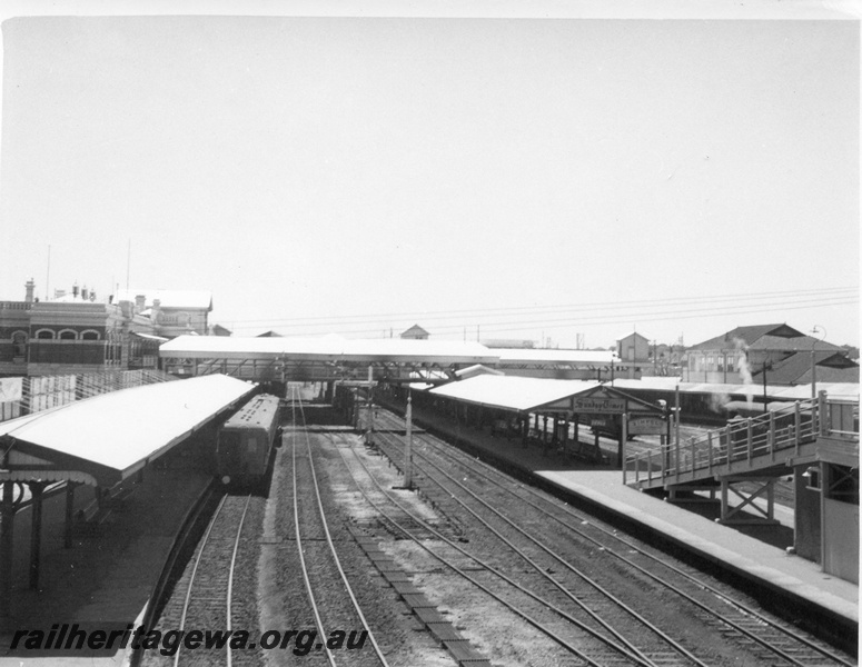 P01748
Perth station, east end, view looking west, ER line, showing platforms, covered pedestrian bridge, advertising boards, diesel railcar set.
