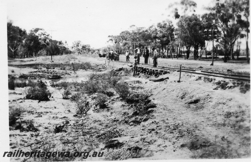 P02129
5 of 7 views of flooding and washaways on the Narrogin to Wagin section of the GSR, Workers standing on a section of track supported on a 