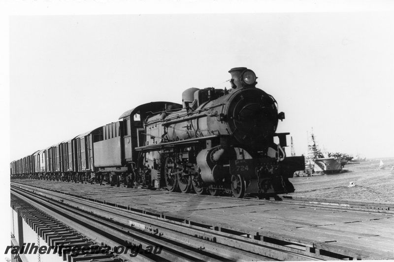 P02536
PMR class 724 steam locomotive, side and front view, crossing the Fremantle bridge, aircraft carrier in the harbour in the background, ER line. circa late 1960s.
