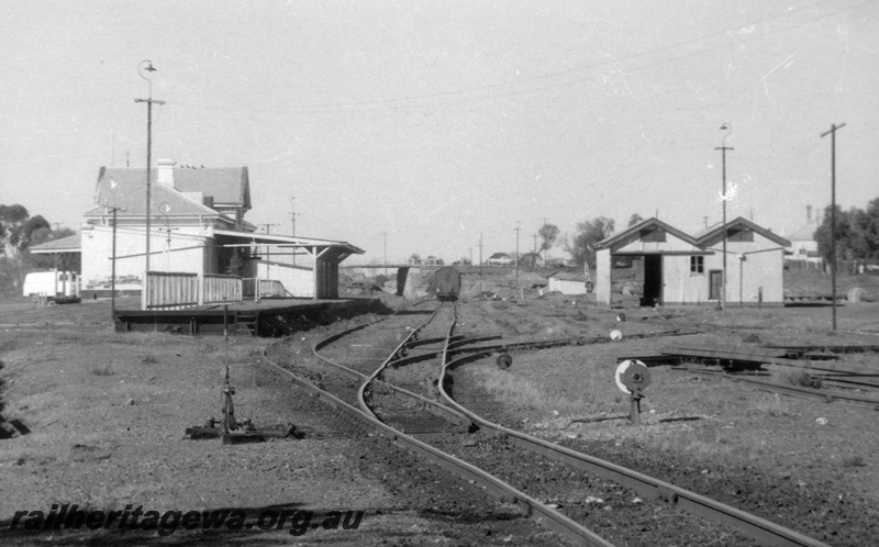 P02915
Yard, passenger platform, points indicator and lever, goods shed, station building, road bridge, lifting the rails, Coolgardie, EGR line, c1970.
