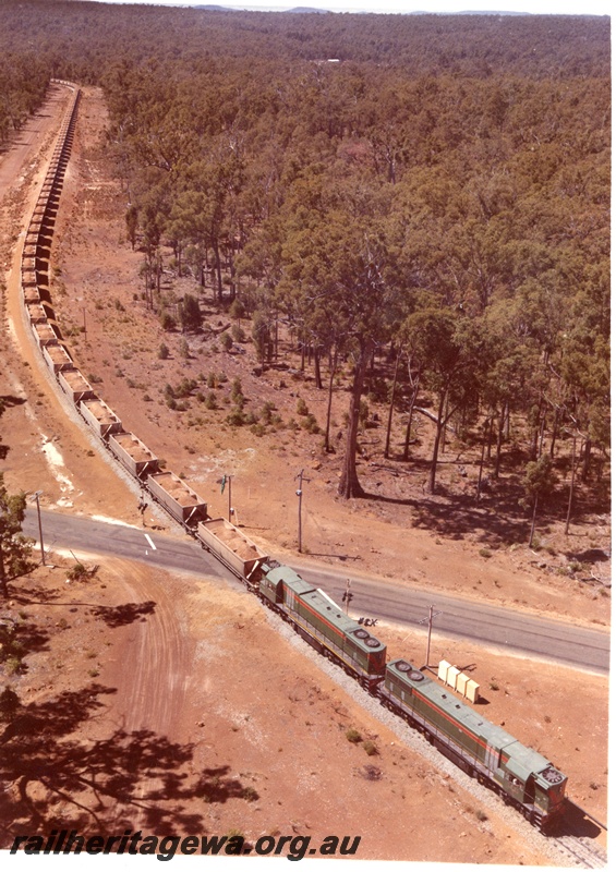 P03779
Double headed D class diesel locomotives in green livery, loaded bauxite train, level crossing aerial view along the train. 

