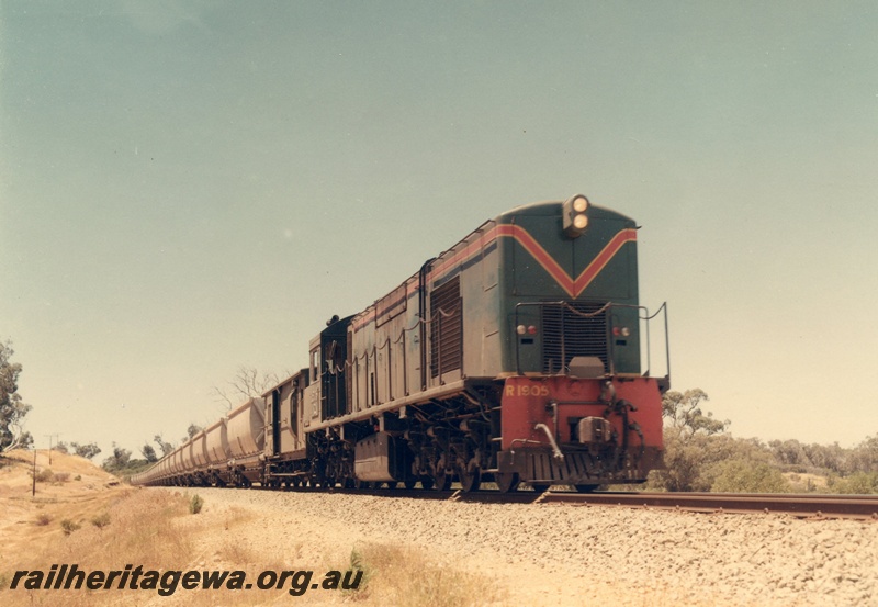 P03886
2 of 2, R class 1905 diesel locomotive on bauxite train, green with red and yellow stripes livery, running long hood first, side and front view, XC class bauxite hoppers.
