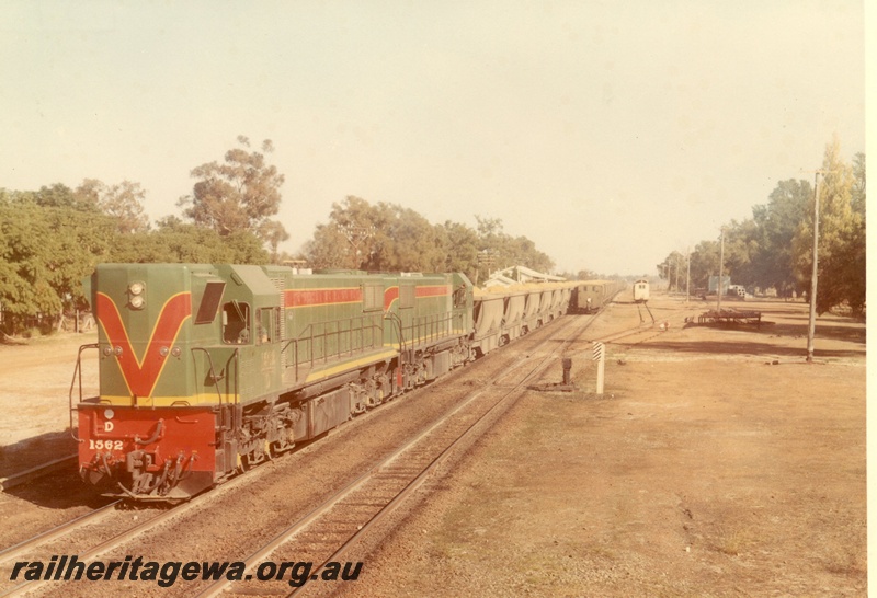 P03933
D class 1562 diesel locomotive double heading with another diesel locomotive, hauling a bauxite train of XBC class wagons, in green with red and yellow stripe livery, front and side view.
