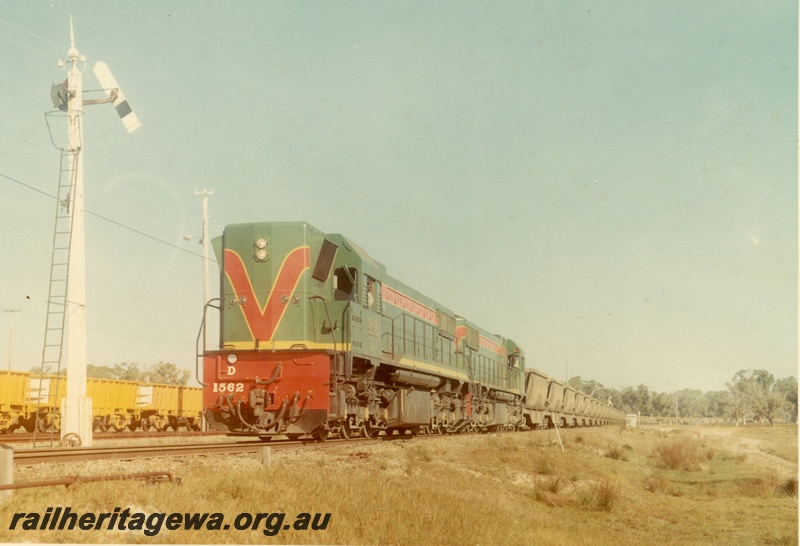 P03936
D class 1562 diesel locomotive in the green with red and yellow stripe livery double heading with another diesel locomotive, hauling a bauxite train of XBC class wagons, semaphore signal, front and side view.
