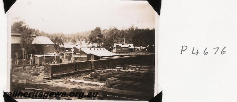 P04676
General view of timber mill showing various buildings and timber stacks
