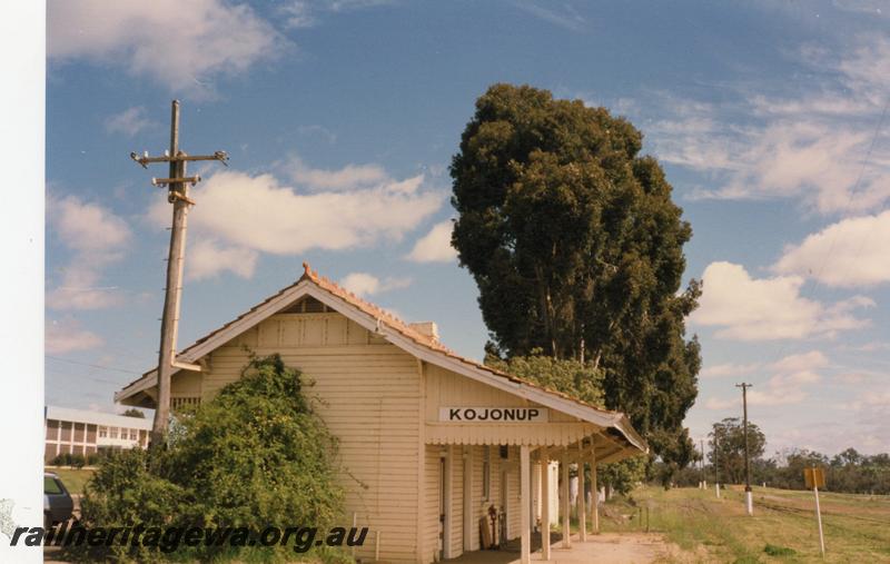 P08487
Kojonup, station building, view along platform, nameboard on fascia, loading ramp in background, DK line.
