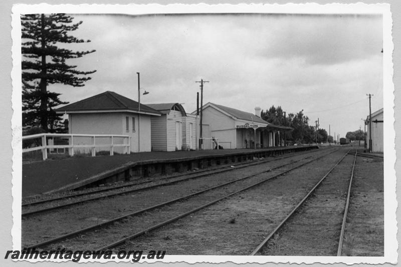 P09435
Busselton, station buildings, platform, nameboard, lever frame on platform, edge of goods shed, wagons in distance in yard. BB line.
