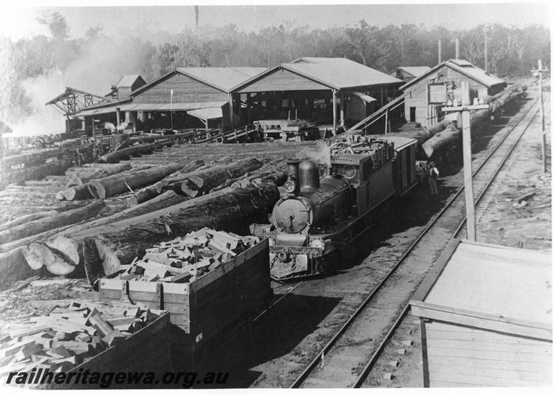 P10183
Millars G type loco, on log train, wagons filled with off cuts, log skids, timber mill, Jarrahdale, elevated view over mill 
