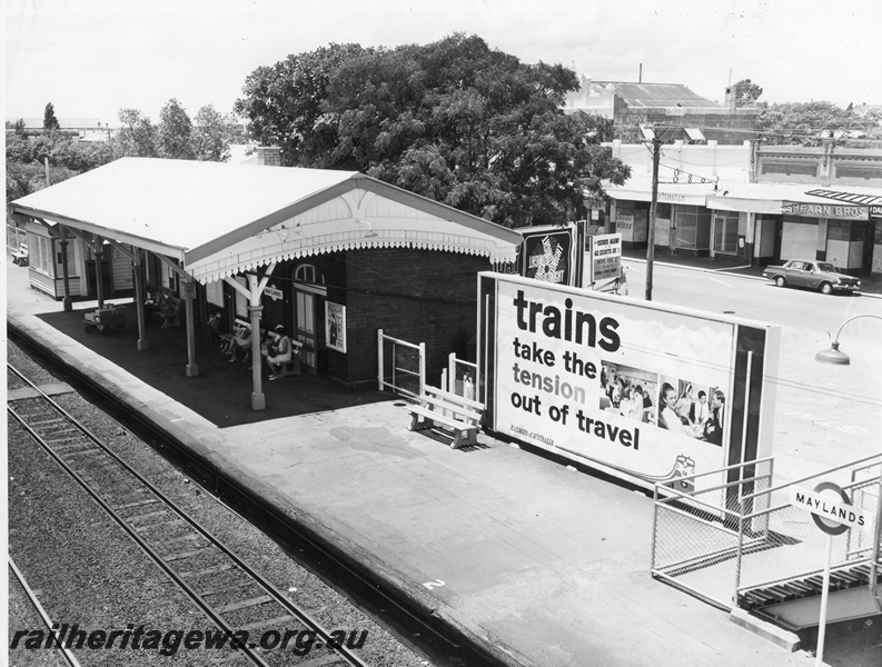 P10408
Three quarter view of Maylands station taken from footbridge showing advertising signage and shops in background. Portion of signal box also visible.
