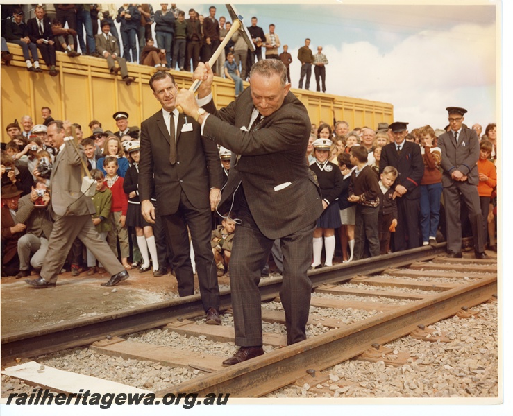 P10632
(Sir) David Brand, State Premier, spiking the 'gold' dog spike to link the standard gauge railway with the Commonwealth Railway line at Kalgoorlie. Behind Mr Brand is Mr R O'Connor, Minister for Railways.
