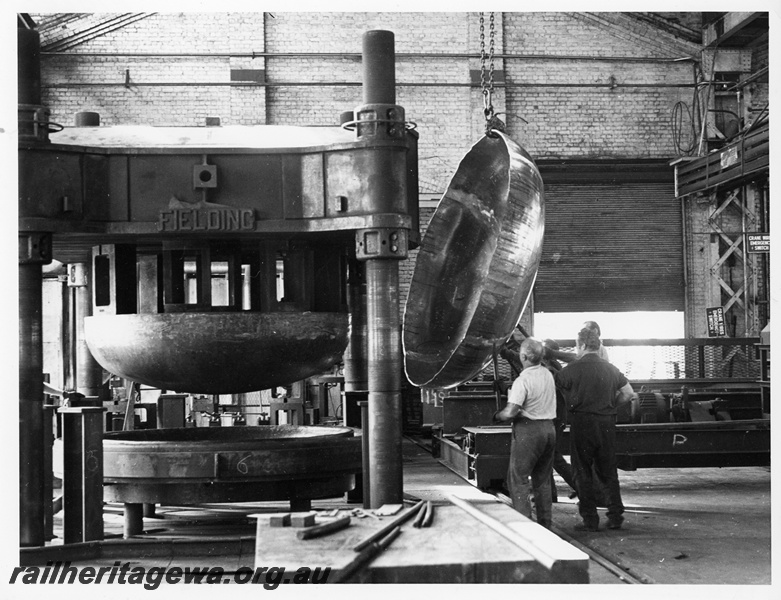 P10650
End of fuel tanker wagon being lifted after pressing, Fielding Press machine, workers, overhead chain, roller door, Midland Workshops, floor level view
