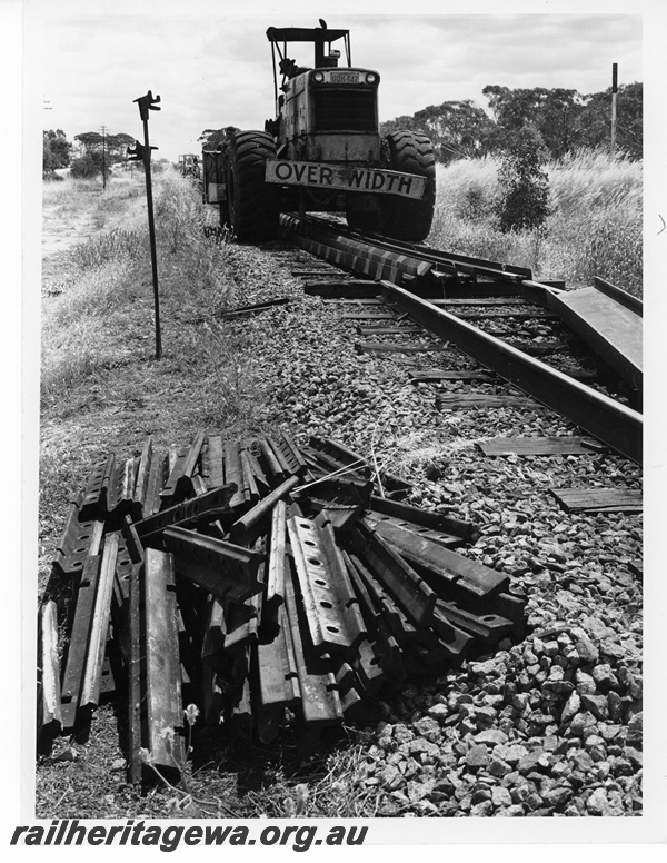 P10663
Narrow gauge track retrieval, fishplates, rails, over width tractor licence no UQH542 with driver, Burracoppin, EGR line
