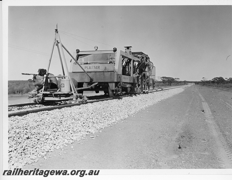 P10668
Plasser ballast tamping machine, on newly ballasted section of track, workers seated on trailer, end and side view
