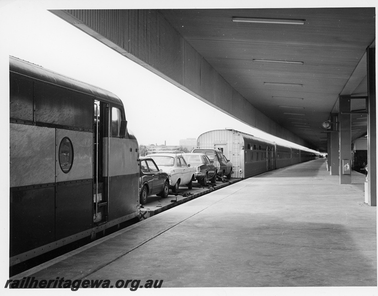 P10670
Commonwealth Railways (CR) GM class diesel (cab portion only), flat bed car transport carriage, rake of stainless steel passenger carriages, platform, canopy, East Perth Terminal, end and side view
