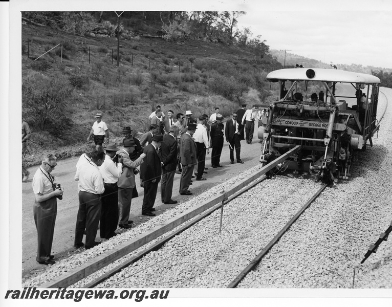 P10675
Conquip and George Moss ballast tamping machine, at work on newly ballasted section of track, operator, party of interested onlookers some in suits and ties, front and side view
