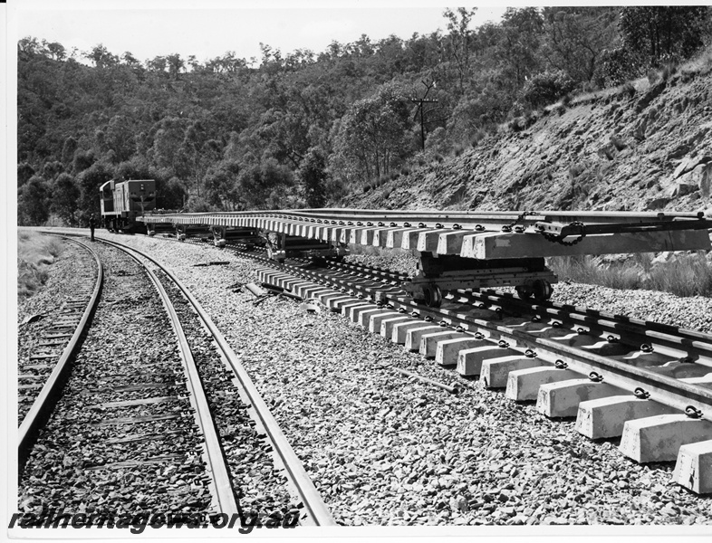P10679
Diesel hauled dual gauge track laying train, carrying section of track with concrete sleepers attached, Avon Valley line, side and end view at track level
