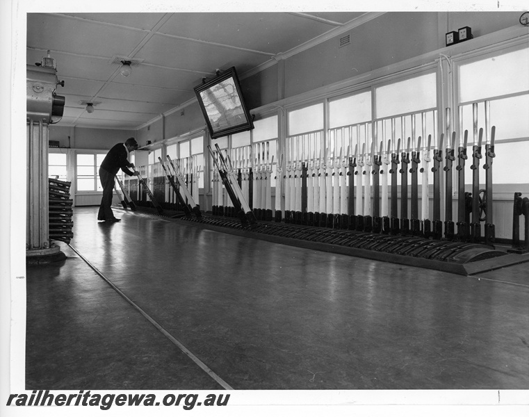 P10779
Interior of signal box, multiple levers and frame, signalling diagram, signalman pulling lever, Brunswick Junction, SWR line
