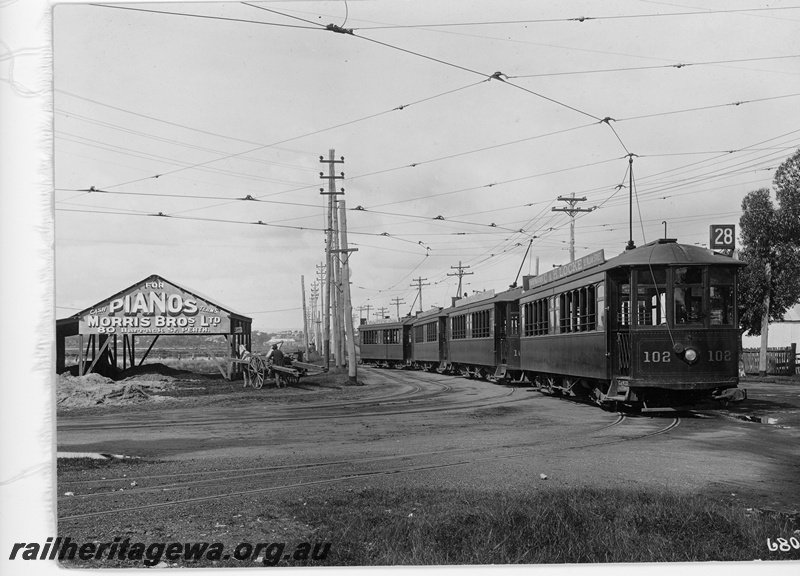 P10873
Four bogie trams, coupled together headed by  number 102, at the East Perth Car Barn. Note advertising on shed.
