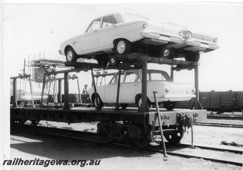 P10879
Commonwealth Railways (CR) R type flat wagon, fitted with car carrying frames, being unloaded to WAGR flat top wagons, at Parkeston. Note the frame work for carrying cars on an upper level.
