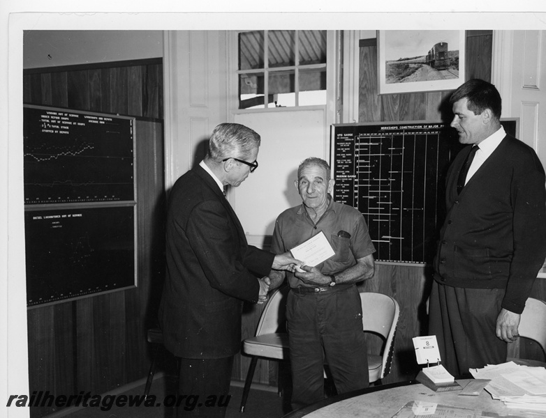 P10945
Midland Workshops Furnaceman, Mr C Burnett, being presented with the 'Wise Owl Club' safety award by the Chief Mechanical Engineer, Mr W C Blackeney-Britter with the Works Manager looking on.
