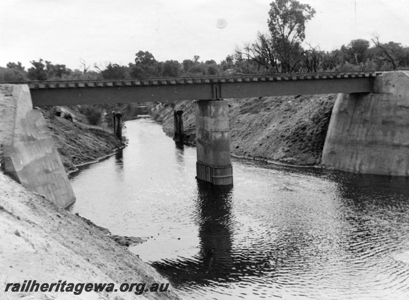P12034
12 of 12 images of the construction of the Kwinana to Jarrahdale railway. (ref: The Railway Institute Magazine, July 1963).No.1 bridge at Wellard with the remains of a bridge on the original line in the background.
