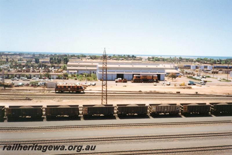 P12533
View from Port Hedland Nelson Point Yard Control tower looking north, of Goldsworthy Mining A class English Electric loco on road float leaving site, Mount Newman Mining EM80 track recorder car, loaded unmodified ore cars
