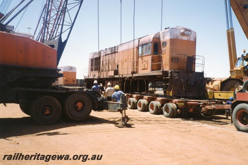 P12537
Port Hedland Nelson Point yard, Goldsworthy Mining A class English Electric No.5 being loaded onto a Bell road float for transporting to Perth as riggers direct the crane drivers
