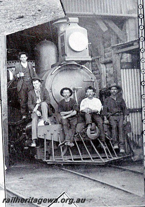 P12930
G class with large oil headlight, Geraldton Loco Depot, head on view with workers on the headstock. the image is extracted from the Geraldton Loco Depot Christmas Card/poster from 1897.
