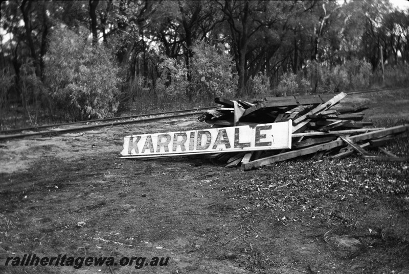 P13327
Station nameboard on ground, remains of the shed in the aftermath of a bushfire, Karridale, BB line.
