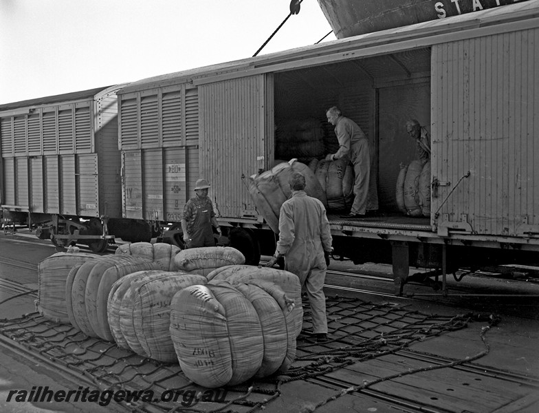 P14474
VF class wagons, unloading wool, Fremantle Harbour, shows workers handling the wool bales.
