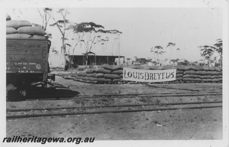 P14507
GC class wagon with ridge pole, bagged wheat stack with a large banner with the name of the wheat buying company 