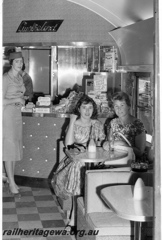 P14975
AYD class Australind Buffet Car interior view showing Stewardess and passengers in 1950s dress style.
