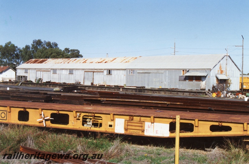 P15464
The Westrail Rail Siding with large shed with a loading platform, piles of rails and other items scattered around the site, part view of a WFX wagon in the foreground, Bellevue, mainly a side on view of the shed.
