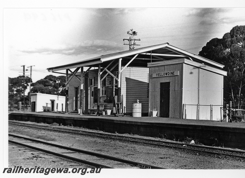 P16699
Station building under an overall canopy roof, Out of Sheds on the platform, another shed at the end of the platform, nameboard,  seat, baggage trolley, Yellowdine, EGR line, view along the platform.

