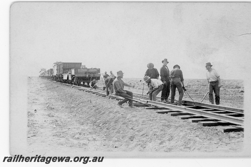 P16807
Commonwealth Railways (CR) - TAR line track workers manually securing rail to sleepers. Construction train in background. c1916
