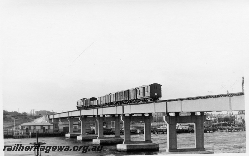 P17168
X class type diesel locomotive on a goods train crossing the Fremantle rail bridge, white tail disc on the back of the brakevan, ER line. 
