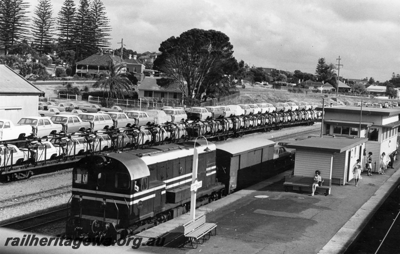 P17174
F class 44 diesel locomotive in MRWA livery, front and side view on goods train, passing through Cottesloe, passenger shelter shed, signal box, platform furniture, loaded QMD class car carriers on siding, Cottesloe ER line.
