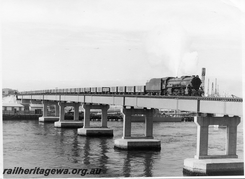 P17178
V class loco, on goods train No 56, crossing metal and concrete bridge, wharves and boats on the Swan River below, Fremantle, ER line
