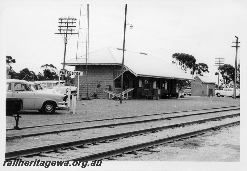 P17552
Station building, trackside shed, hand luggage trolley, cars parked, station sign, Parkeston, TAR line, c1968 
