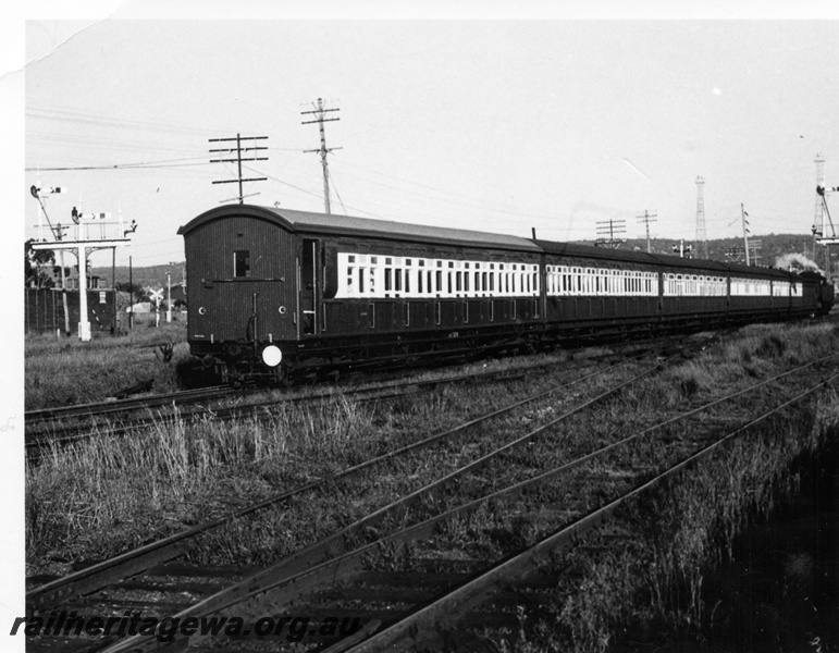P17635
Suburban steam hauled set consisting of side loading (dog box) carriages with an unidentified AU carriage at rear. Midland. Note semaphore signals to left and right of train.

