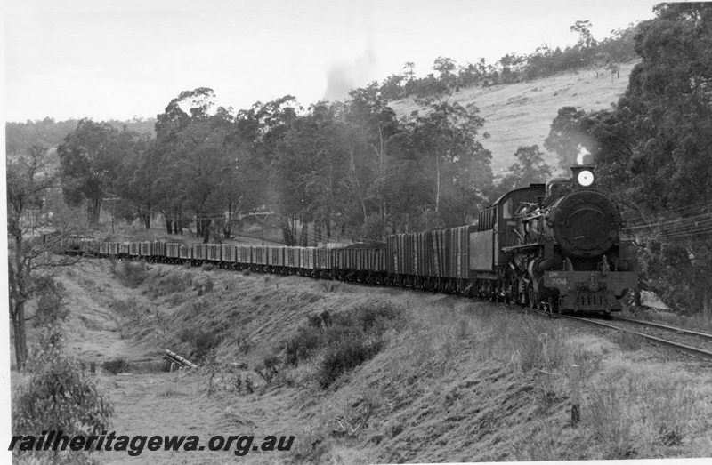 P17828
PM class 704 steam locomotive at 'Dead Tree Curve' with 168 goods travelling from Collie to Brunswick Junction. BN line. It appears the leading wagons are loaded with coal.
