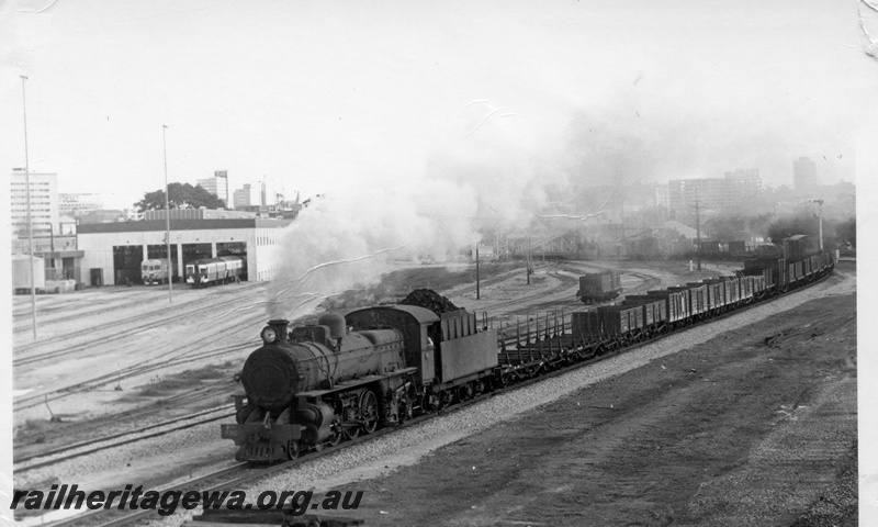 P17829
PMR class 730 steam locomotive departing East Perth with 35 goods train for Bunbury. SWR line. Note the railcars at the railcar shed and the yard trackage then present. In the foreground is the abandoned formation for the line to the East Perth Power house.
