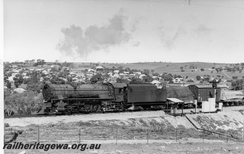 P17831
V class 1215 steam locomotive working 24 goods from York. GSR line. The train is crossing the Avon River bridge at Northam. Note the automatic signal, telephone box and shaded water tank.
