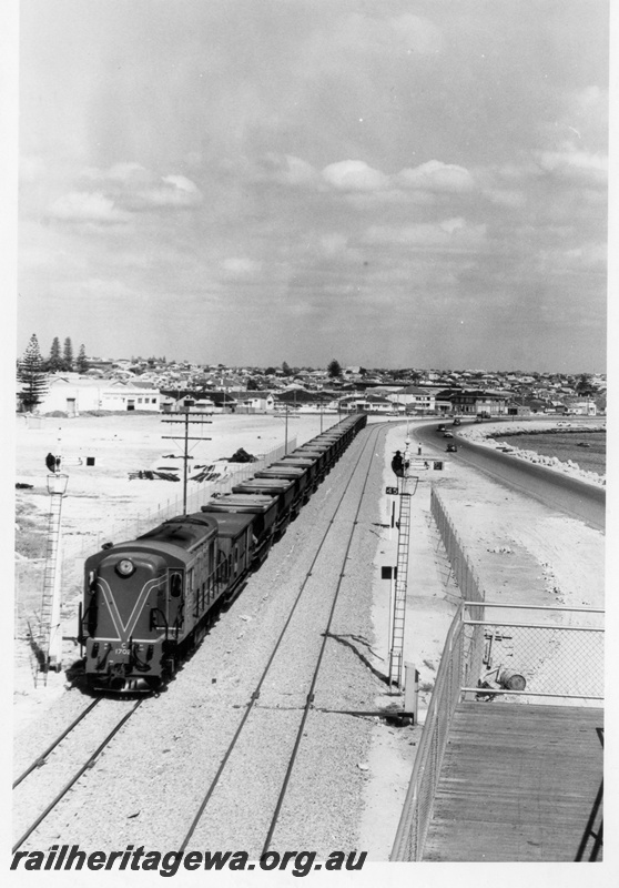 P17837
C class 1702 diesel locomotive hauling a rake of empty bauxite wagons through Fremantle. FA line. Overhead view of train with semaphore signals in foreground and portion of footbridge ramp. 
