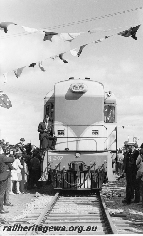 P17842
K class 207 diesel locomotive passing over the last link of the standard gauge line at Kalgoorlie. Note the close proximity of the spectators to the locomotive and the coloured bunting. Sir David Brand, State Premier, is at the controls of the locomotive.
